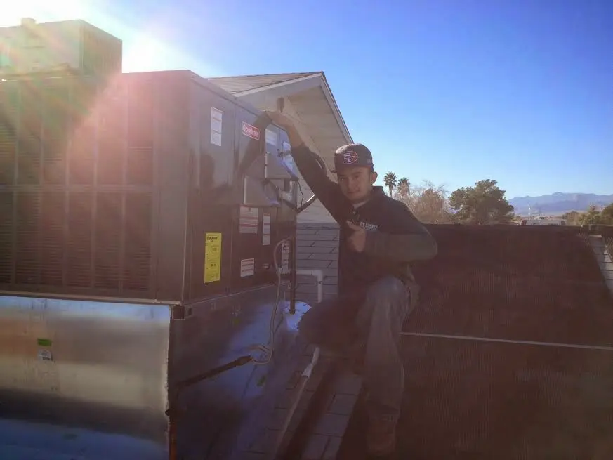 HVAC technician performing Air Duct Cleaning on a rooftop unit in Sherrelwood